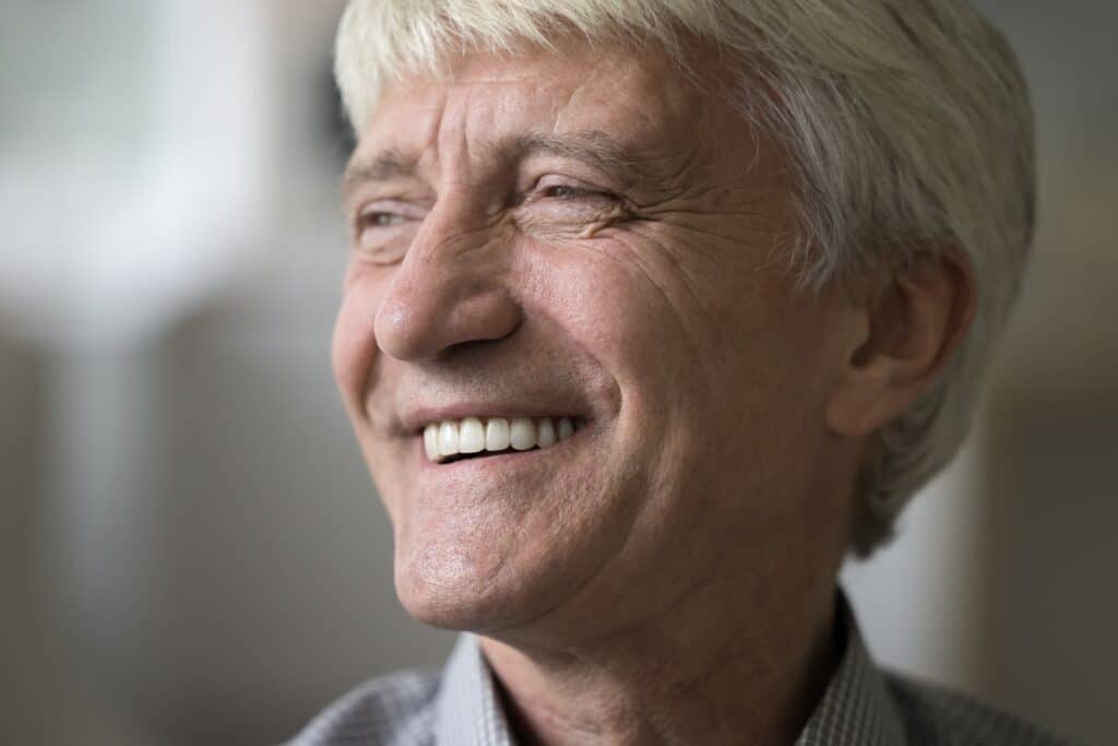 Older man smiling and showing off his snap-on dentures