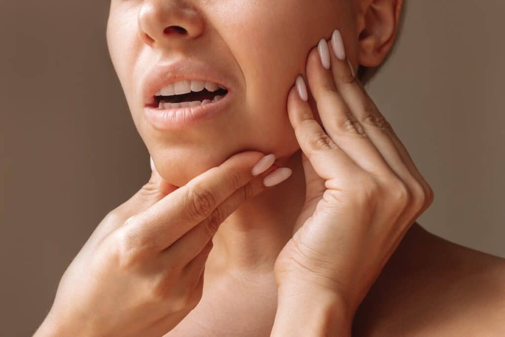 Close up of a woman clutching her jaw in pain from a sever toothache