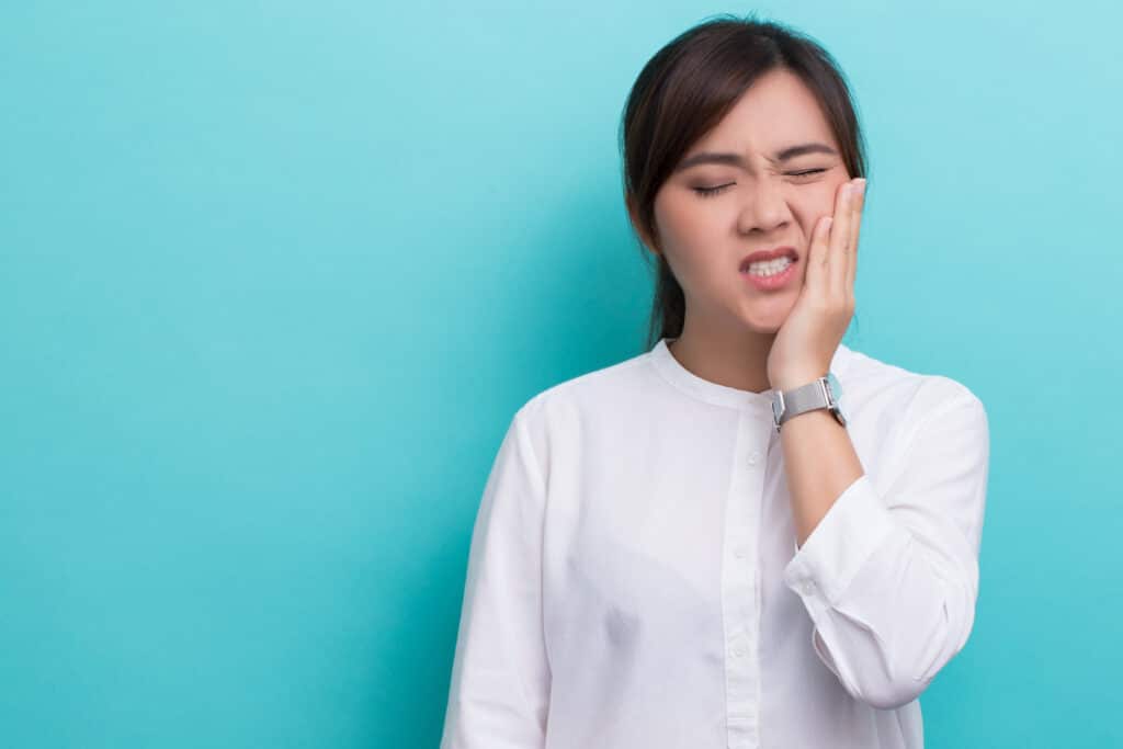Young woman clutching her jaw in pain after chipping her tooth