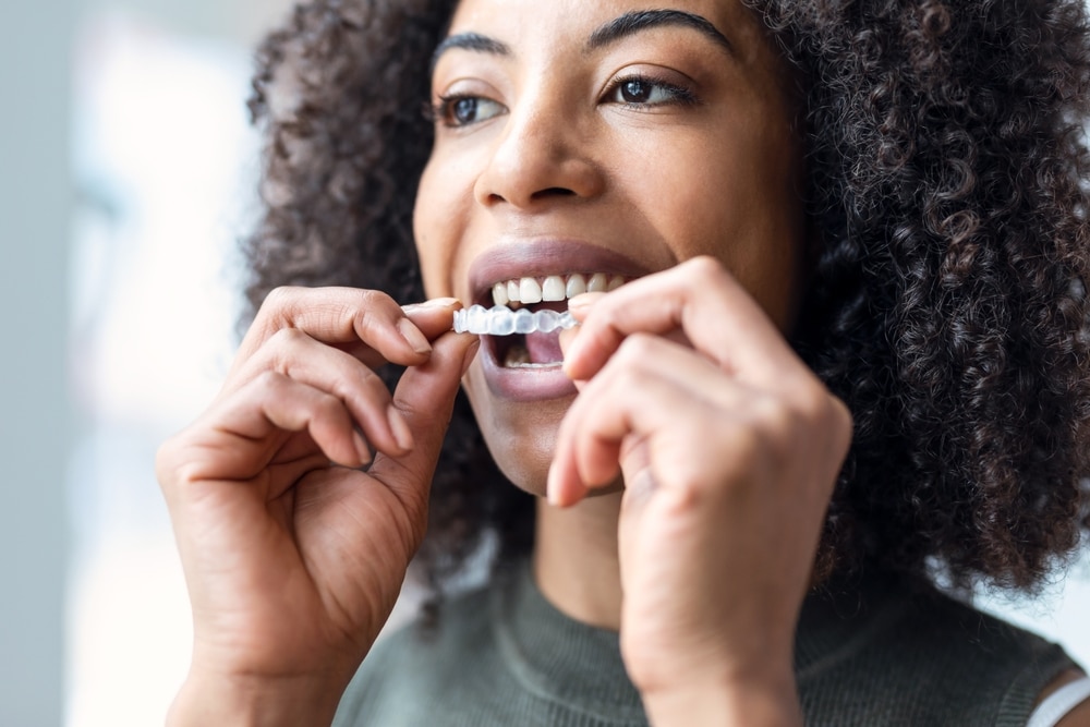Adult woman putting in her Invisalign aligners for discreet, comfortable teeth straightening.