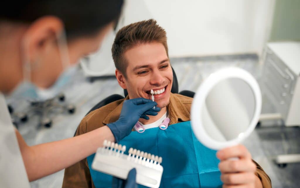 Happy man having his teeth color-matched for dental veneers or crowns