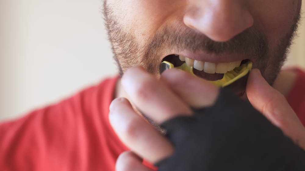 Close-up of a male athlete putting a sports mouthguard on instead of Invisalign during a game.